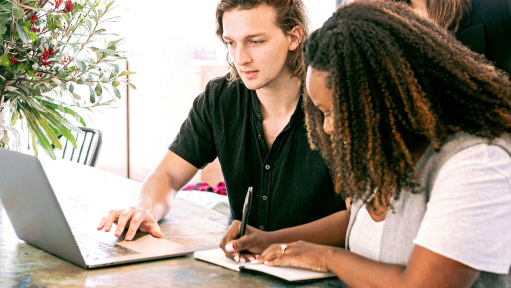 Man Working on Laptop while Woman Takes Notes