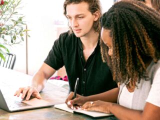 Man Working on Laptop while Woman Takes Notes